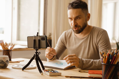 Young man using mobile phone while sitting on table