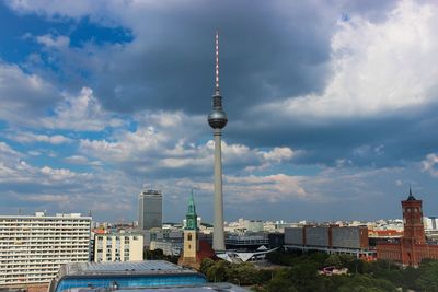 Fernsehturm against cloudy sky in city