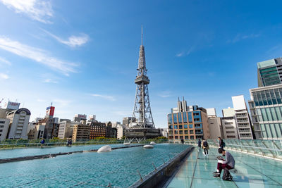 People on swimming pool against buildings in city