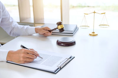 Cropped image of female lawyer doing paperwork at desk in courtroom