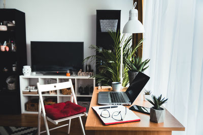 Side view of a laptop on a desk in an empty home office during the day. work from home concept.