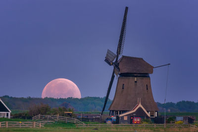 Traditional windmill on field against clear sky moonrise 