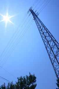 Low angle view of electricity pylon against blue sky