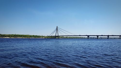 Bridge over sea against clear blue sky