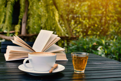 Coffee cup and open book on table at yard