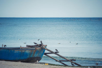 Fishing boat on beach against clear sky