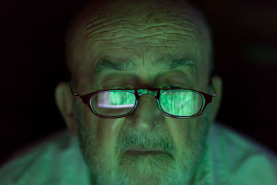 Senior man wearing eyeglasses with reflection of computer