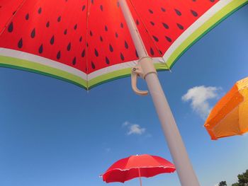 Low angle view of umbrellas against blue sky