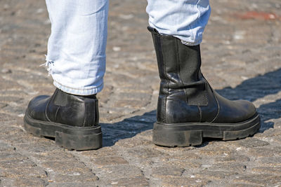 Female with blue jeans in black boots on a street pavement