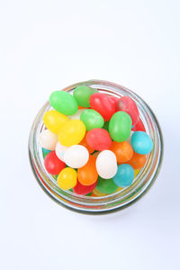 Multi colored candies in bowl against white background