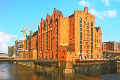 View of buildings by river against sky in city