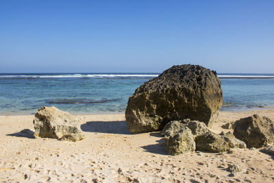 Scenic view of rocks on beach against clear sky