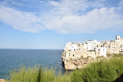 Scenic view of sea by buildings against sky