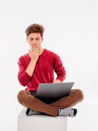 Young man using smart phone against white background