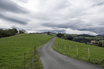 Road amidst green landscape against sky