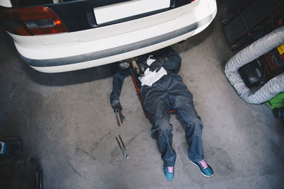 High angle view of mechanic repairing car in workshop