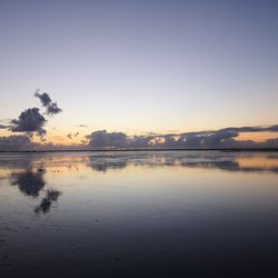 Scenic view of lake against clear sky at sunset