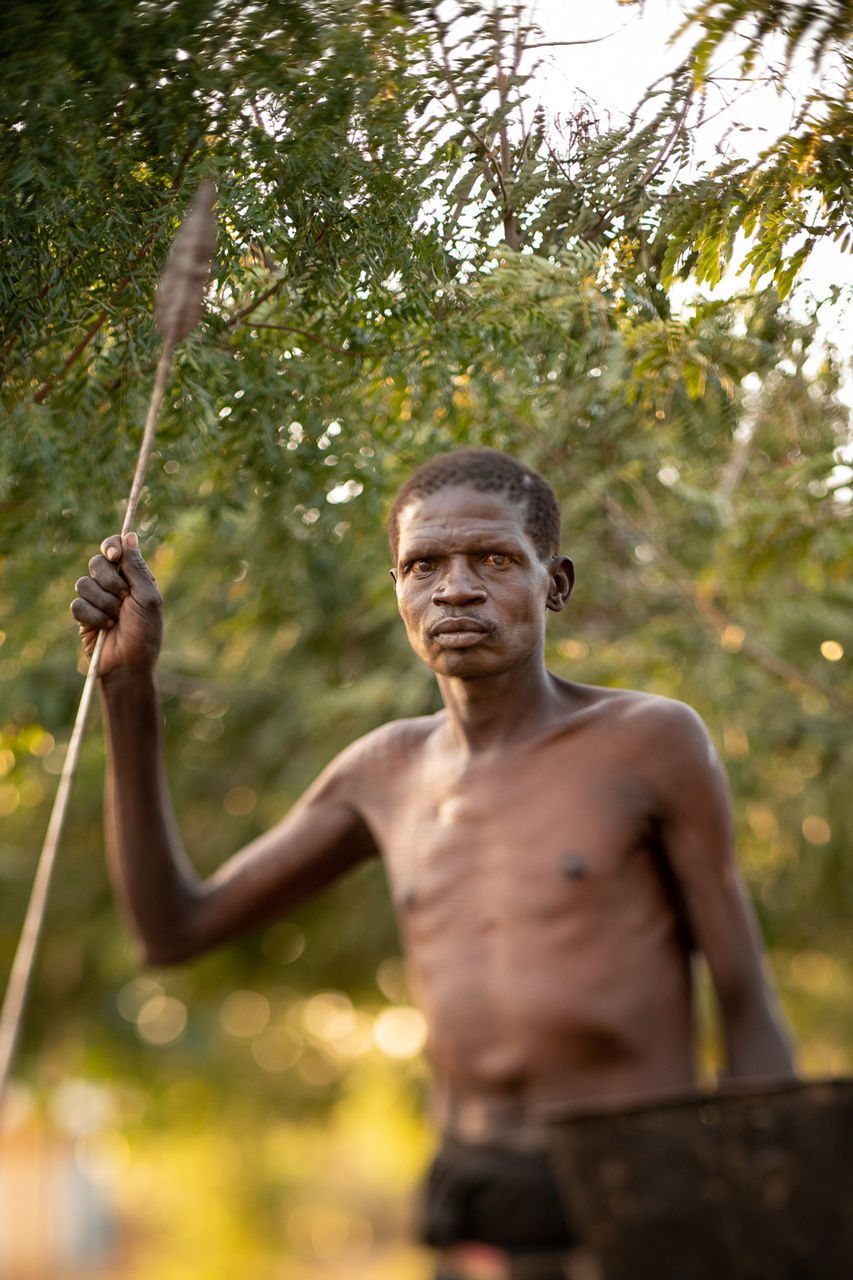 PORTRAIT OF MAN STANDING AGAINST TREE