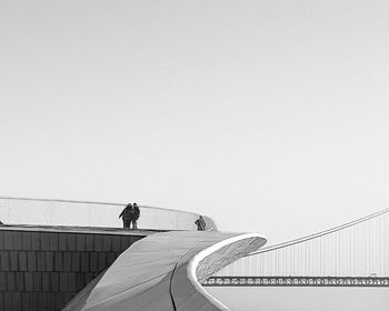 Person standing on bridge against clear sky