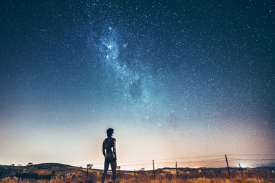 Rear view of naked man standing against star field at night