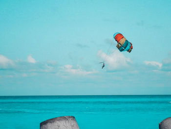 Low angle view of person paragliding over sea against sky