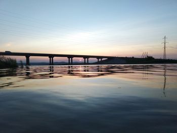 Bridge over river against sky during sunset