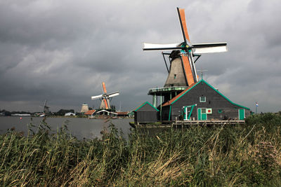 Traditional windmills by field against cloudy sky