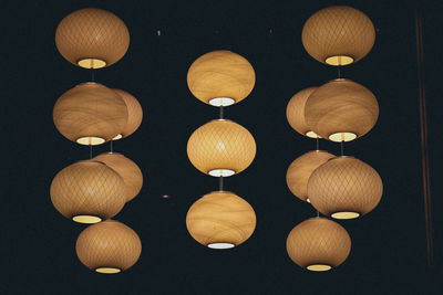 Close-up of light bulbs hanging against black background