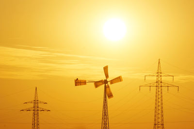 Low angle view of power lines against sky at sunset