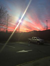 Cars on road against sky during sunset