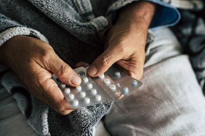 Midsection of woman holding medicine sitting at home