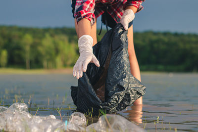 Midsection of woman standing by lake against sky