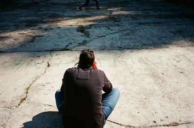 Rear view of man sitting on floor