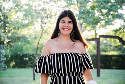 Portrait of happy young woman standing at park