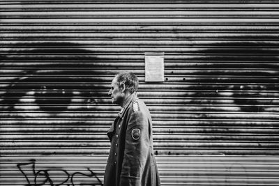 Full length of man standing against closed shutter