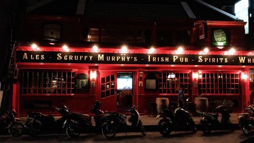 Bicycles parked on illuminated street at night