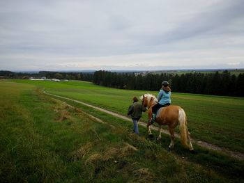 Man riding horse on field against sky