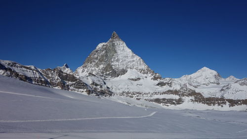 Scenic view of snowcapped mountains against clear blue sky