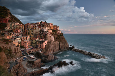 Scenic view of sea by manarola buildings against sky, in cinqueterre