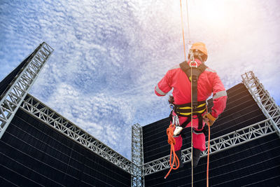 Low angle view of man with arms raised against sky