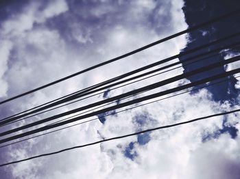 Low angle view of electricity pylon against cloudy sky
