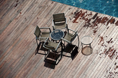High angle view of chairs with table arranged at poolside during sunny day