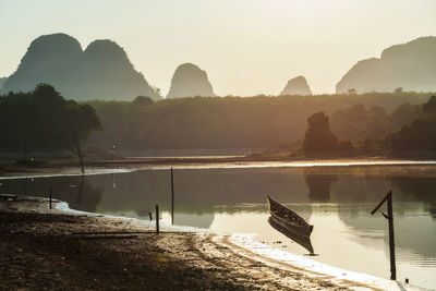 Scenic view of boat on lake against sky during sunrise