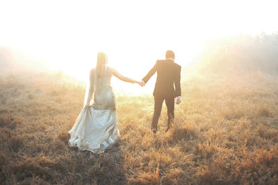 Friends standing on field against bright sun