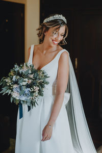 Bride holding bouquet standing against wall