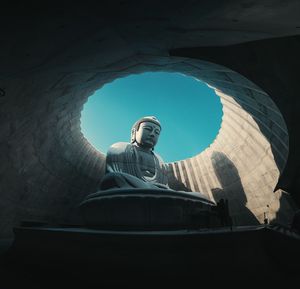 Low angle view of buddha statue in cupola against clear sky