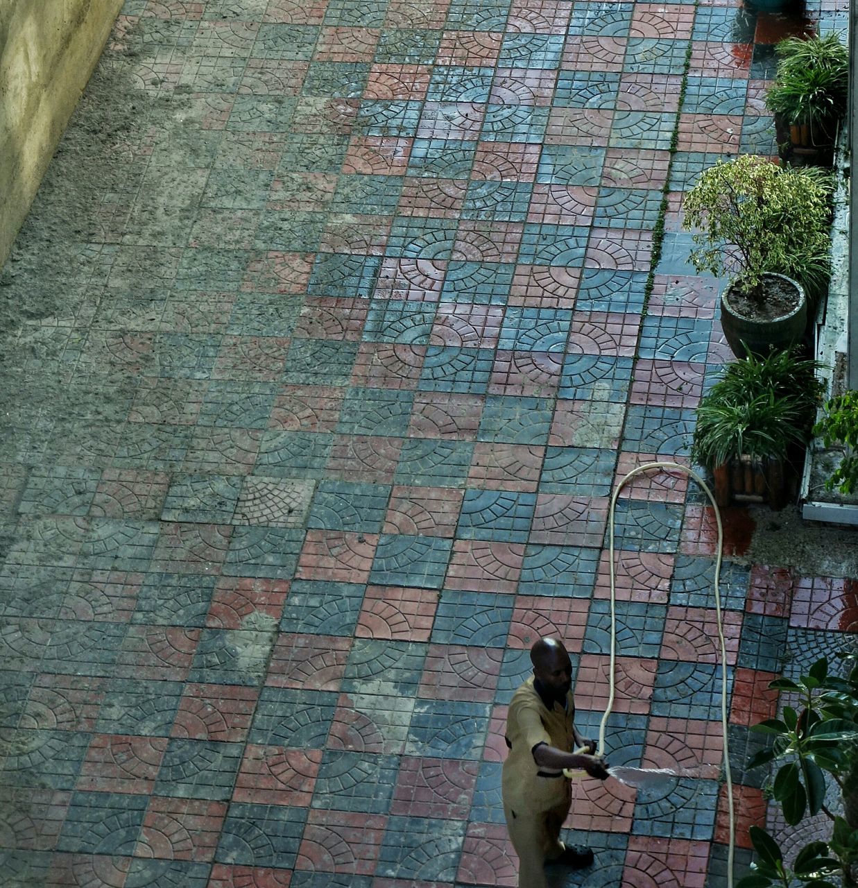 high angle view, cobblestone, paving stone, human representation, day, art and craft, footpath, art, wall - building feature, outdoors, sunlight, one person, shadow, sidewalk, built structure, brick wall, leaf, creativity, architecture