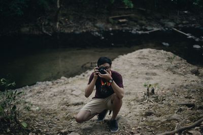 Full length of man photographing while sitting on land