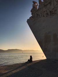 Silhouette people on beach against clear sky during sunset