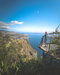 Scenic view of young woman admiring the sea against sky